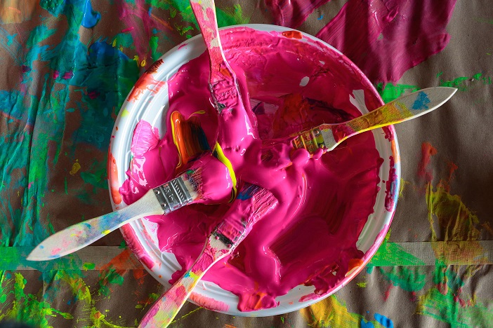 A plate with 4 pink paint soaked brushes